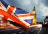 Union Jack flag waving with clock tower in London at dusk