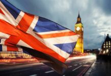 Mini-UK Brexit? Tiny Village ‘Secedes’ Union Jack flag waving with clock tower in London at dusk