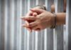 Bogus LGBTQ Claims Trigger London Busts hands in handcuffs behind jail bars