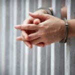 Bogus LGBTQ Claims Trigger London Busts hands in handcuffs behind jail bars