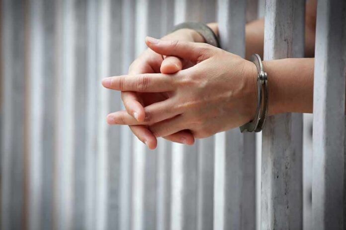 shutterstock_1031018551-4 hands in handcuffs behind jail bars