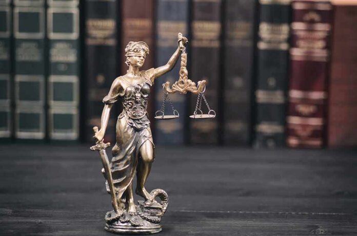 shutterstock_1112412905 Lady Justice statue with scales in front of law books