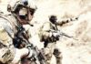 Soldiers in camouflage gear with rifles in a sandy terrain