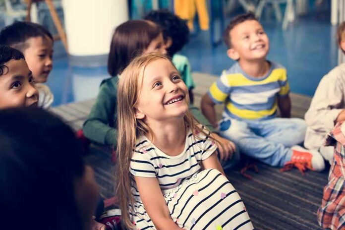 Group of children sitting on a classroom floor smiling