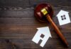 Judge's gavel with paper house cutouts on wooden table