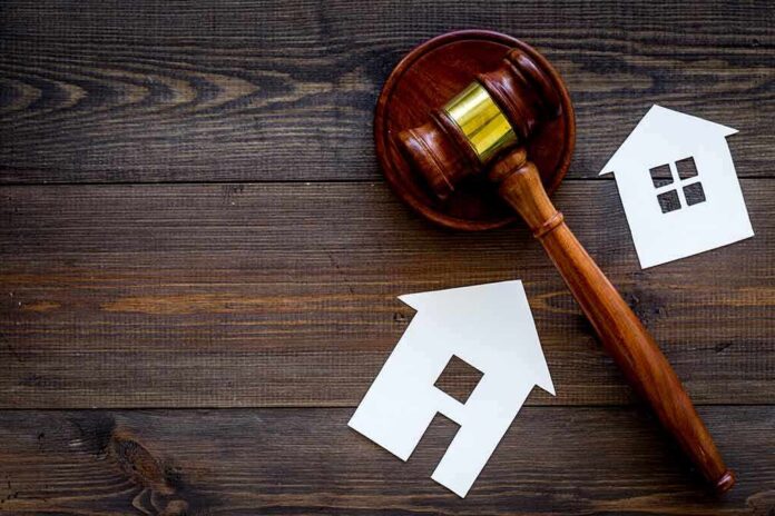Judge's gavel with paper house cutouts on wooden table
