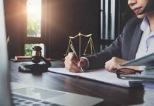 Lawyer writing at desk with gavel and scales