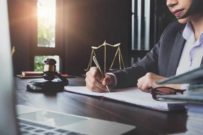 Lawyer writing at desk with gavel and scales