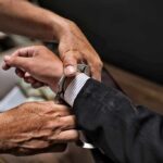 hands placing handcuffs on a suited person's wrists