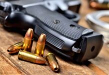 Handgun with scattered bullets on wooden surface