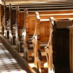 Shocking Church Attack – Gunmen Storm Mourner Crowd wooden church pews in sunlight