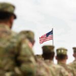 Iran War Tab: What’s Not Counted? U.S. flag flying above a formation of soldiers in uniform