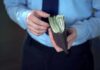 Big Family Paydays – Osborn’s Risky Bet Person in dress shirt holding a wallet stuffed with cash