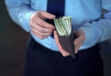 Big Family Paydays – Osborn’s Risky Bet Person in dress shirt holding a wallet stuffed with cash
