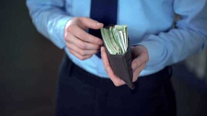 Person in dress shirt holding a wallet stuffed with cash