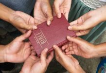Non-Christians ‘Out’? Senate Bombshell Erupts Multiple hands holding a red Bible