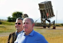 Ehud Barak and another man outdoors near a missile defense battery