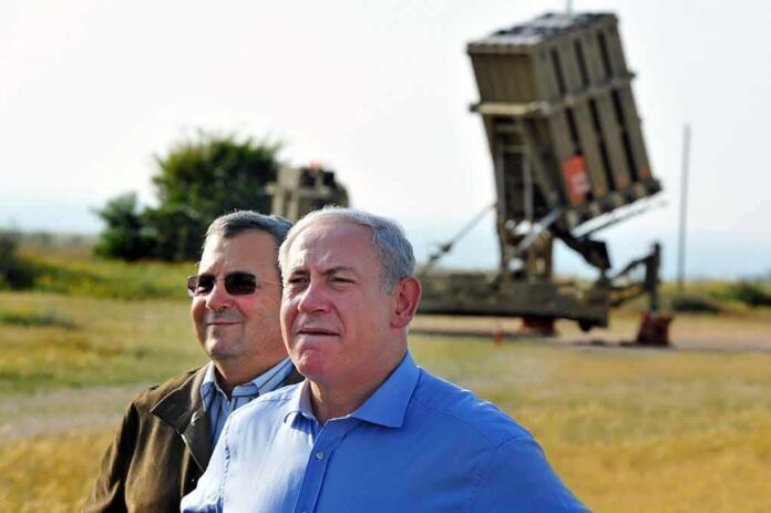 Ehud Barak and another man outdoors near a missile defense battery
