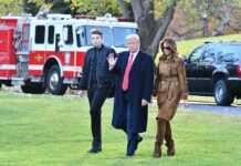 Donald Trump and Melania Trump walk across a lawn with another person