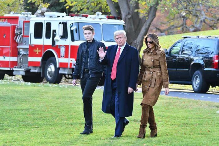 Donald Trump and Melania Trump walk across a lawn with another person