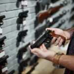 Gun Shop Panic: Chilling ICE Threats – Lawyer Nabbed Fast Person holding a handgun in a gun shop