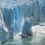 Doomsday Hype Fizzles – Danger Still Creeps A glacier calving into the ocean, creating a splash of ice and water