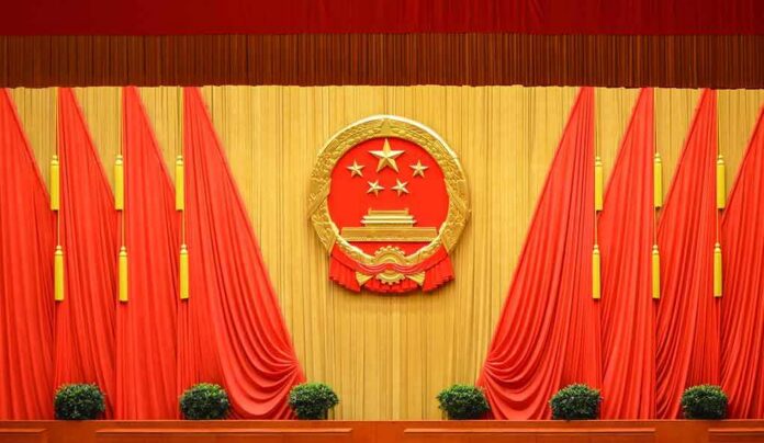 shutterstock_1697991220 Chinese national emblem on red-draped stage backdrop