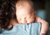 Newborn baby sleeping on an adult's shoulder