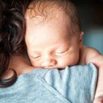 Newborn baby sleeping on an adult's shoulder