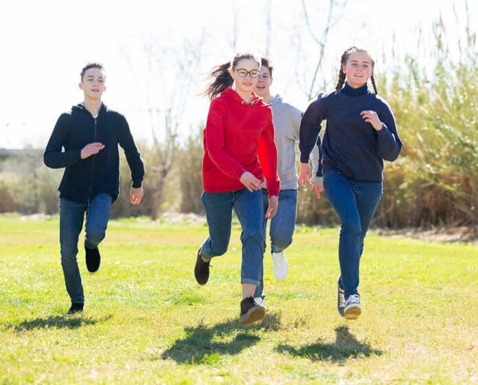 shutterstock_1902606307 Group of teens running outdoors on a sunny day