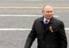 man in dark coat with ribbon walking outdoors