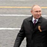 Humanitarian? Putin Praise Ignites DC Firestorm man in dark coat with ribbon walking outdoors
