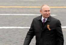 man in dark coat with ribbon walking outdoors