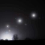 Pentagon Files – FBI Agents Stunned By Soundless Triangle Night sky over a silhouetted landscape with glowing orbs of light