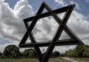 Large Star of David sculpture in a park under cloudy sky