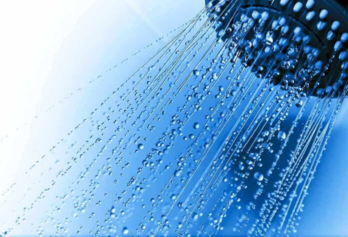 shutterstock_62951839 Close-up of a shower head with water droplets against a blue background